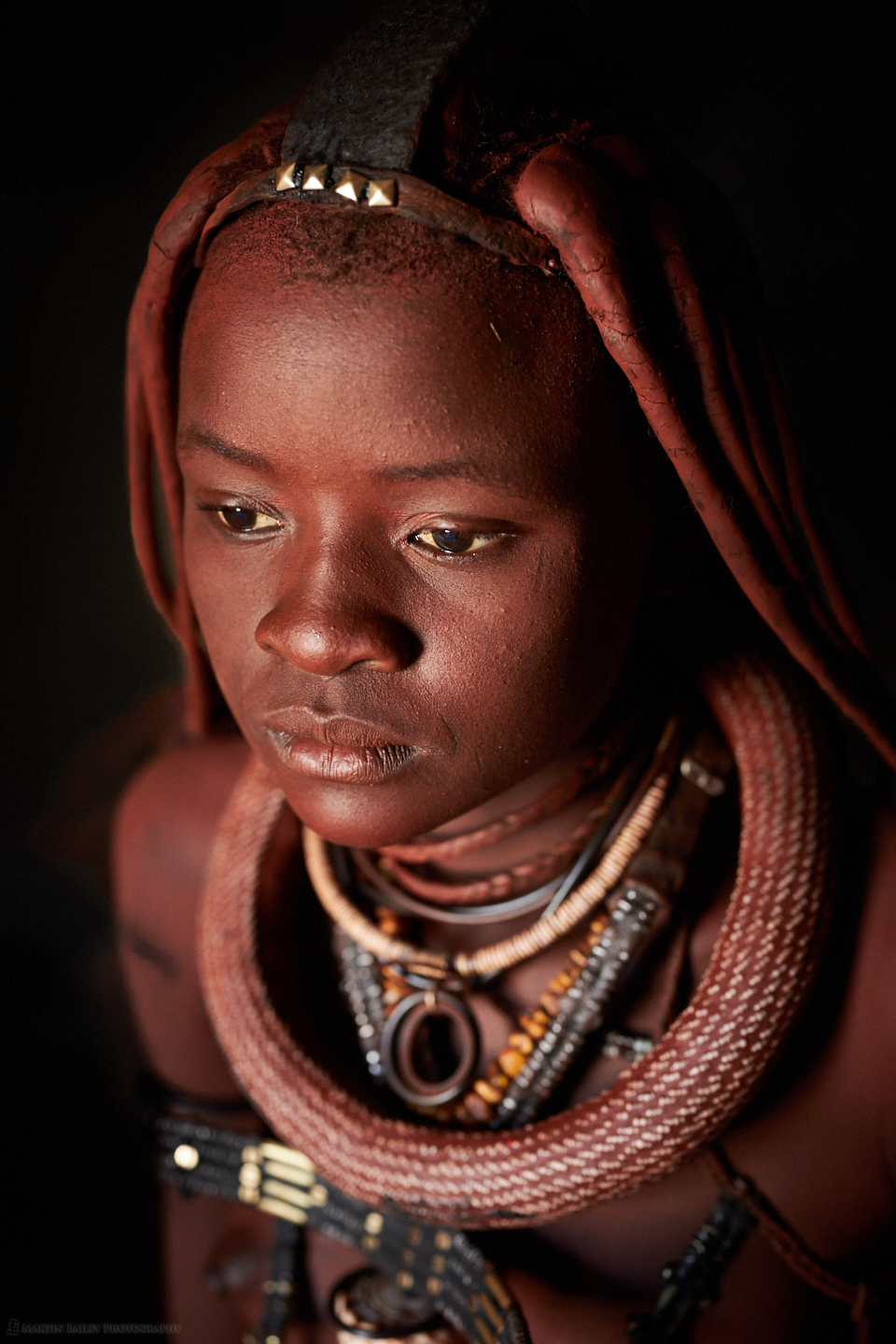 A young Himba lady caught in a moment of thought
